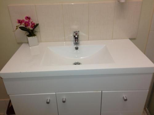a white sink sitting under a mirror in a bathroom at Carnegie Motor Inn in Carnegie