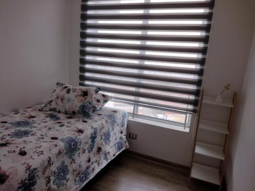 a bedroom with a bed and a window with blinds at Hermoso departamento Cerro los placeres Valparaíso in Valparaíso