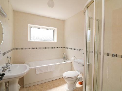 uma casa de banho com uma banheira, um WC e um lavatório. em Tilladavin House em Tomhaggard