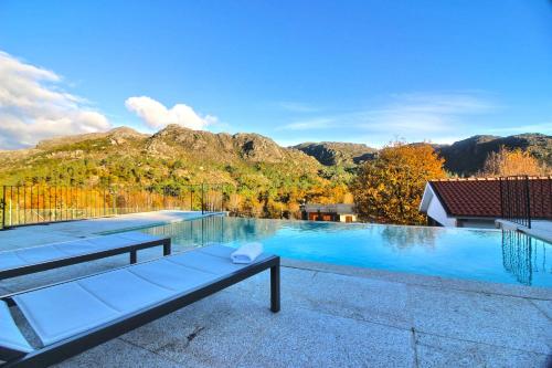 a large swimming pool with mountains in the background at Casa Fraga do Suadouro in Campo do Gerês