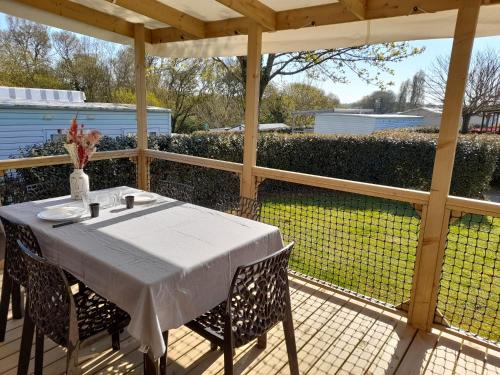 una mesa blanca con sillas en el patio en mobil home neuf dans camping 4* avec piscine en La Plaine-sur-Mer