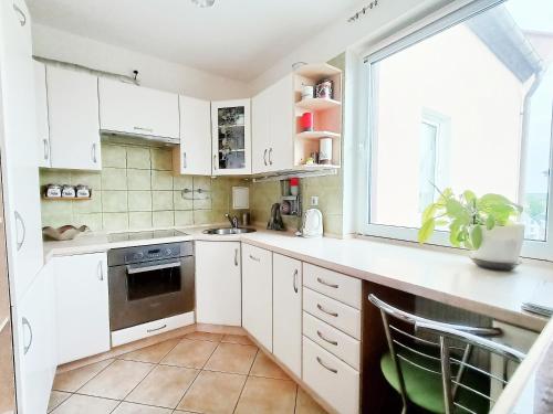 a kitchen with white cabinets and a window at Apartament na Srebrnej in Olsztyn
