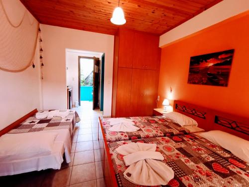 two beds in a room with orange walls at IRIS STUDIOS in Agios Nikitas
