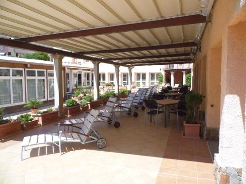 eine Außenterrasse mit Stühlen, Tischen und Fenstern in der Unterkunft Le Nereidi Hotel Residence in La Maddalena
