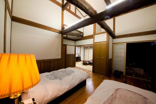 1 dormitorio grande con 2 camas y lámpara en Hatago Kounokura, en Yufu