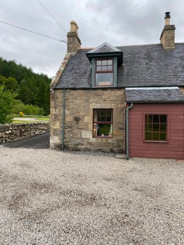 an old stone house with a red garage at Quirky Highland Cottage with Stunning Views in Wester Fearn