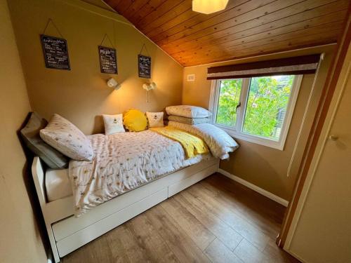 a bedroom with a bed in a room with a window at Bumble Bee Cabin in South Cerney