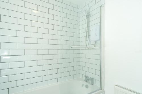 a white tiled bathroom with a shower and a tub at Heath House in Burton upon Trent