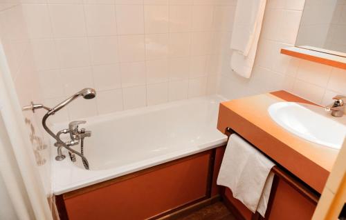 a bathroom with a bath tub and a sink at Résidence Odalys Tourotel in Val Thorens