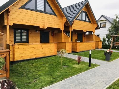 a house with a wooden fence in the yard at Delfinek - Domki Apartamenty in Gąski