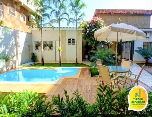 a patio with a table and an umbrella next to a pool at Ecos Conforto in Porto Velho