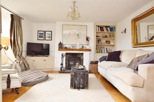 a living room with a white couch and a fireplace at Quintessential Cottage near Bath, Grade 2 Listed. in Paulton