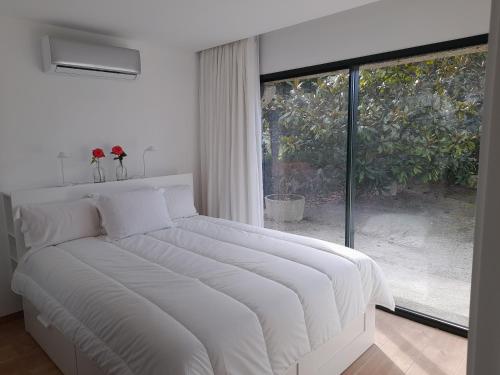 a white bed in a room with a large window at Casa/Apartamento de hóspedes in Viana do Castelo