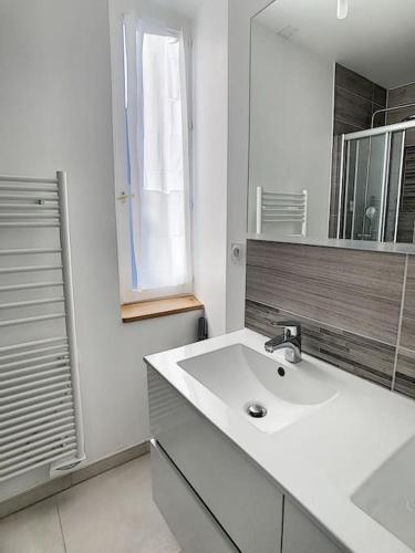 une salle de bain blanche avec un lavabo et un miroir dans l'établissement Les Mouettes. Appart Honfleur 4 personnes vue pont de Normandie, à Honfleur