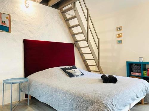 une chambre avec un lit avec une tête de lit rouge et un escalier dans l'établissement Cocon Familial Proche Disneyland Paris, à Quincy-Voisins