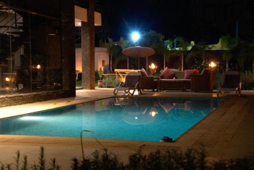 a swimming pool at night with chairs and an umbrella at La Perle de l'Ourika in Ourika