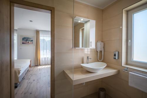 a bathroom with a sink and a bed and a mirror at Füred Centrum Panzió in Balatonfüred