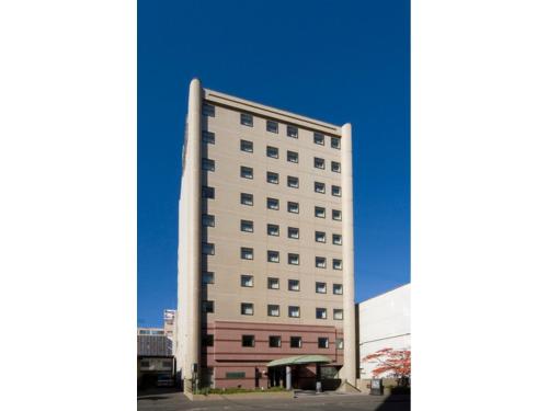 a tall white building sitting next to a parking lot at Kitami Pierson Hotel - Vacation STAY 54802v in Kitami