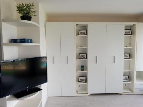 Il comprend un salon doté de placards blancs et d'une télévision à écran plat. dans l'établissement Eliana Appartment, à Menton