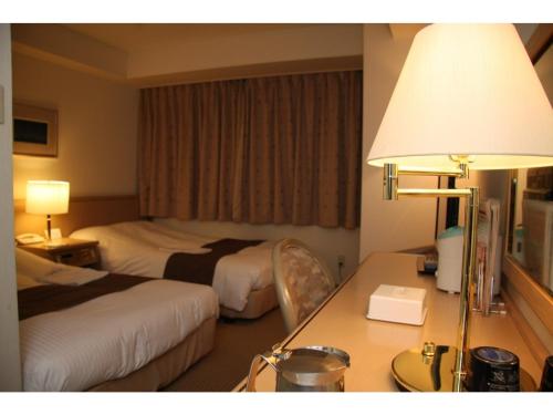 Kitami Pierson Hotel - Vacation STAY 54806v في كيتامي: غرفة فندقية بسريرين ومكتب فيه مصباح