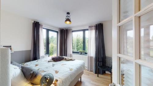 een slaapkamer met een bed en een groot raam bij Bauwerd12, met hottub in de voerstreek in Voeren