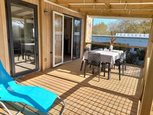 a patio with a table and chairs on a deck at mobil home neuf dans camping 4* avec piscine in La Plaine-sur-Mer