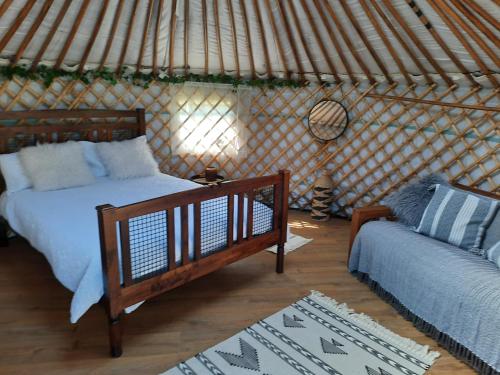 a bedroom with a bed and a couch in a yurt at Cranfield Retreat & Glamping - Yurt & Shepherds Hut in Long Melford
