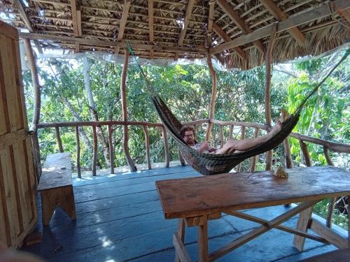 a man laying in a hammock on a porch at Hostel Del Lago Yojoa Backpackers in Agua Azul