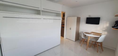 - une cuisine blanche avec une petite table et un réfrigérateur dans l'établissement Studio confort ensoleillé - FAME Marina baie des Anges, à Villeneuve-Loubet