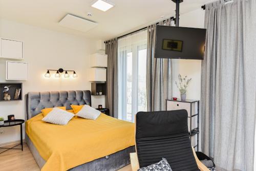 a bedroom with a yellow bed and a chair at La Mer Palanga apartamentai su baseinu ir terasa in Palanga