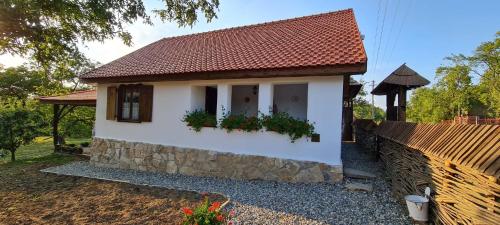a small white house with a stone wall at Acul în carul cu fan in Pădurenii