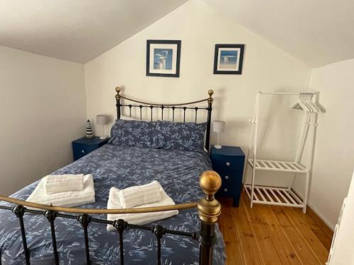 a bedroom with a bed with a blue comforter at Honeysuckle Cottage by The Sea in Mousehole