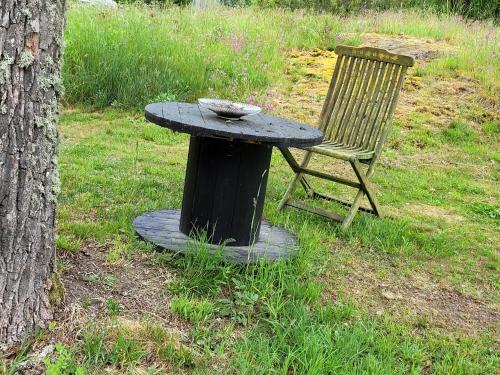 a table and a chair sitting next to a tree at Blankaholm 25 in Blankaholm