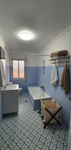 Baño azul con bañera y lavamanos en CASA_VISI, en Gordoncillo