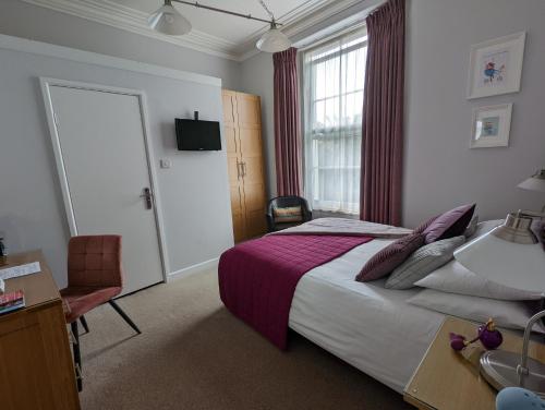 a bedroom with a bed and a desk and a window at Villa Marina in Torquay