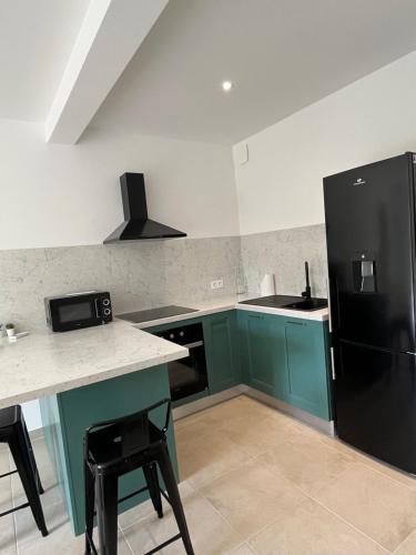 - une cuisine avec des placards verts et un réfrigérateur noir dans l'établissement Appartement Soveria, à Soveria