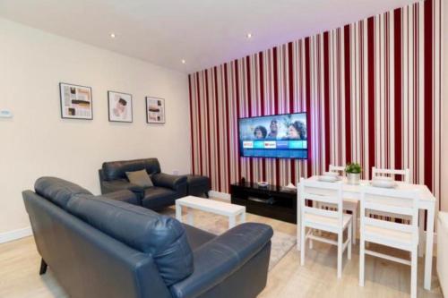 a living room with a couch and a table and a television at Dior House Apartments in Leeds