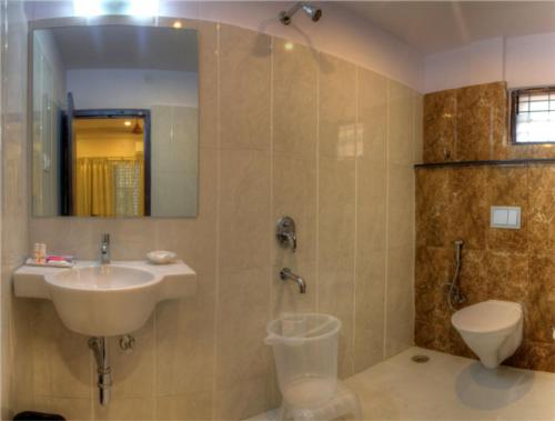 a bathroom with a sink and a shower and a toilet at Hotel Aditya in Mysore