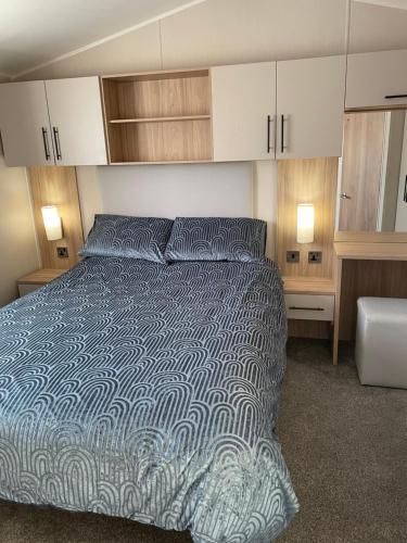 a bedroom with a bed with a blue and white comforter at Dune View Caravan in Lossiemouth