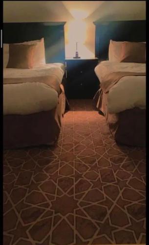a bedroom with two beds and a table with a lamp at هتان السودة Hattan Al Soudah in Suda
