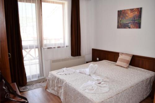een slaapkamer met een bed met witte lakens en een raam bij Двустаен апартамент Горски кът Банско in Bansko