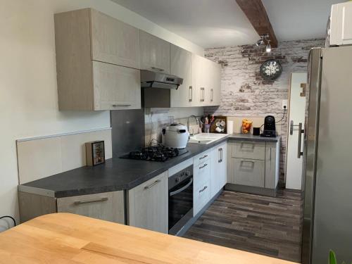 a kitchen with white cabinets and a stove top oven at Le Cocon des Hortillonnages d'Amiens in Camon