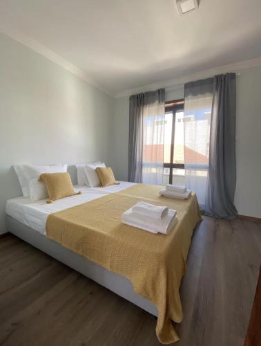 a bedroom with a large bed with towels on it at AMARÉ Guest House in Ovar
