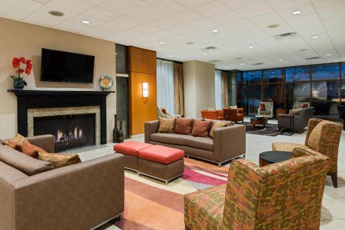 a lobby with a fireplace and couches and a tv at Holiday Inn Knoxville West - Cedar Bluff Rd by IHG in Knoxville