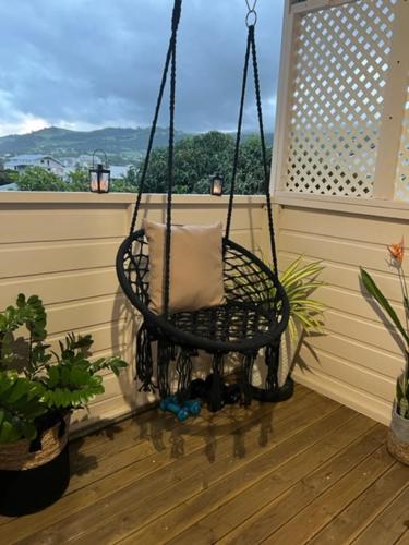 a porch swing with a pillow on a balcony at Le Liseron Créole - Entre Terre, Mer et Rivière - proche toutes commodités in Saint-Joseph