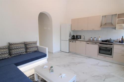 a living room with a blue couch and a kitchen at Plaka Philoxenia Apartments in Plaka Milou