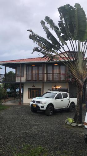 a white car parked in front of a house with a palm tree at El Filito in San JosÃ©