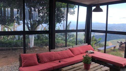 a red couch sitting in a room with windows at El Filito in San JosÃ©