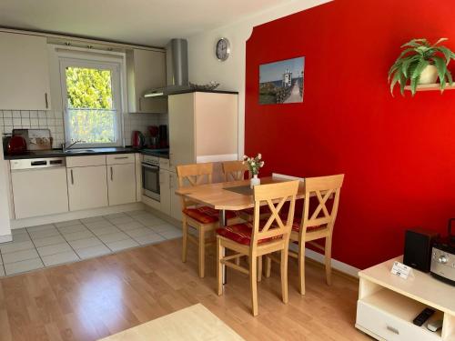 Semi-detached house, Lubmin في لوبمين: مطبخ مع طاولة وجدار احمر