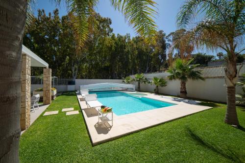 een achtertuin met een zwembad en een gazon bij Villa Perla del Mare in Alcamo Marina